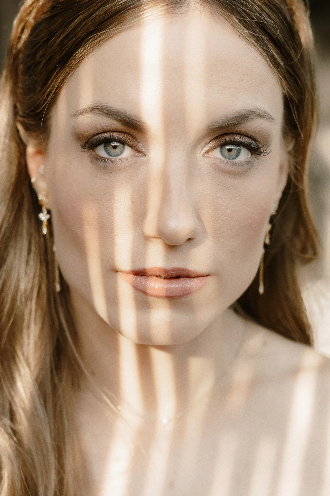 Sunlight weaves delicate shadows across a bride’s serene face in Puglia, her blue eyes reflecting the magic of Italy.