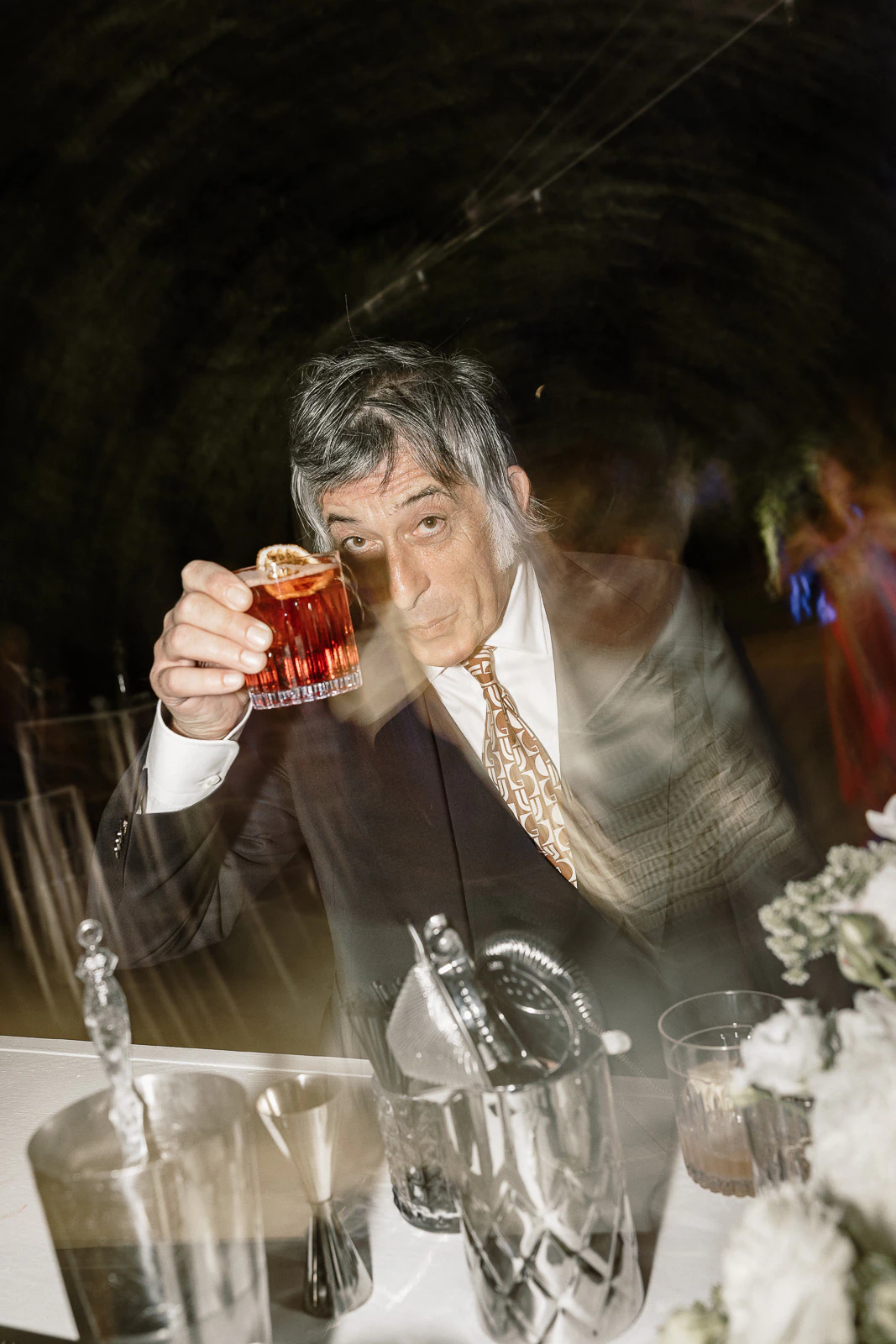 An elegantly dressed guest toasts with a cocktail, capturing the vibrant atmosphere of a Puglia wedding celebration.