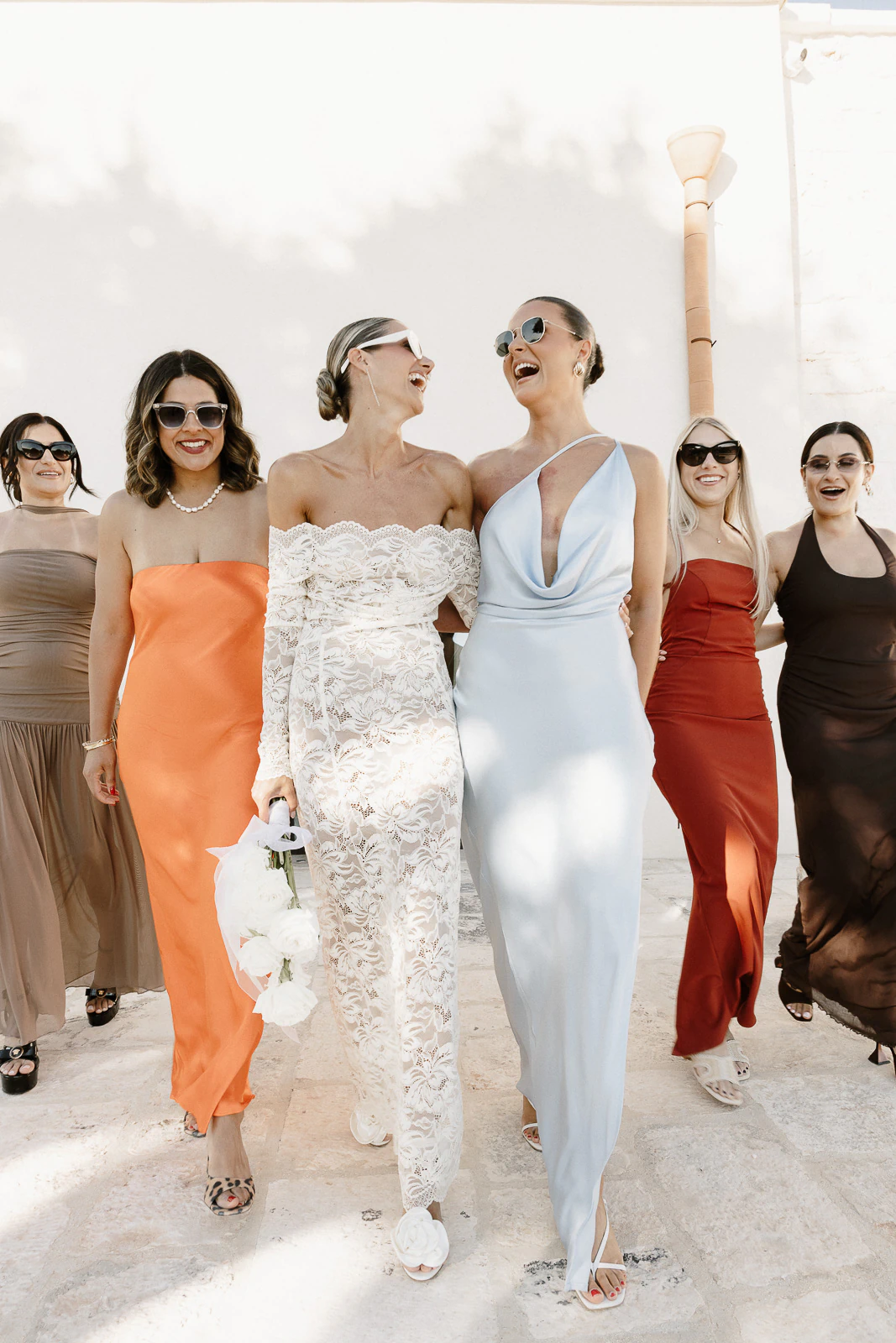 In sun-drenched Puglia, a radiant bride and her bridesmaids share laughter and style during an unforgettable Italian celebration.