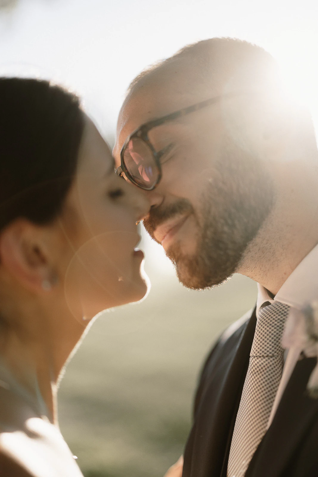 Bathed in golden Italian sunlight, a couple gently touch noses, sharing an intimate smile amid Puglia’s romantic landscape.