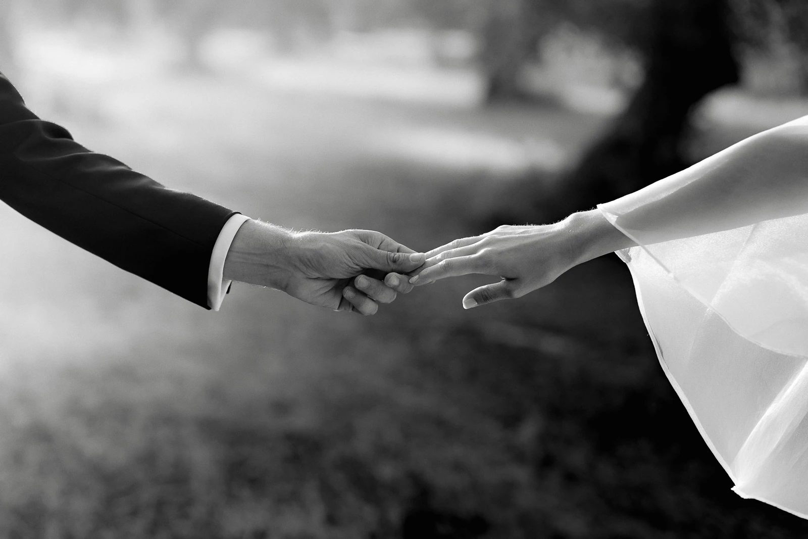 Elegant newlyweds touch hands in a luminous Italian setting, capturing intimate connection amid the romantic landscape of Puglia.