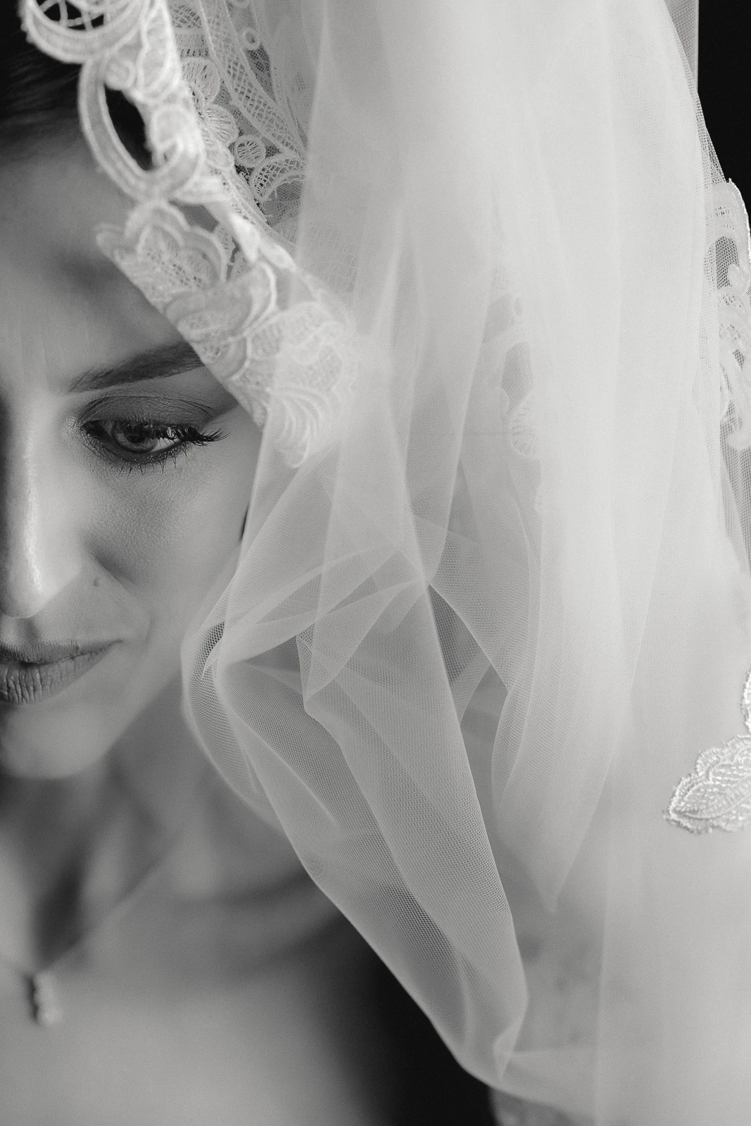 In Puglia, an elegant bride’s gaze is softly veiled in intricate lace, capturing intimate Italian wedding romance in black and white.