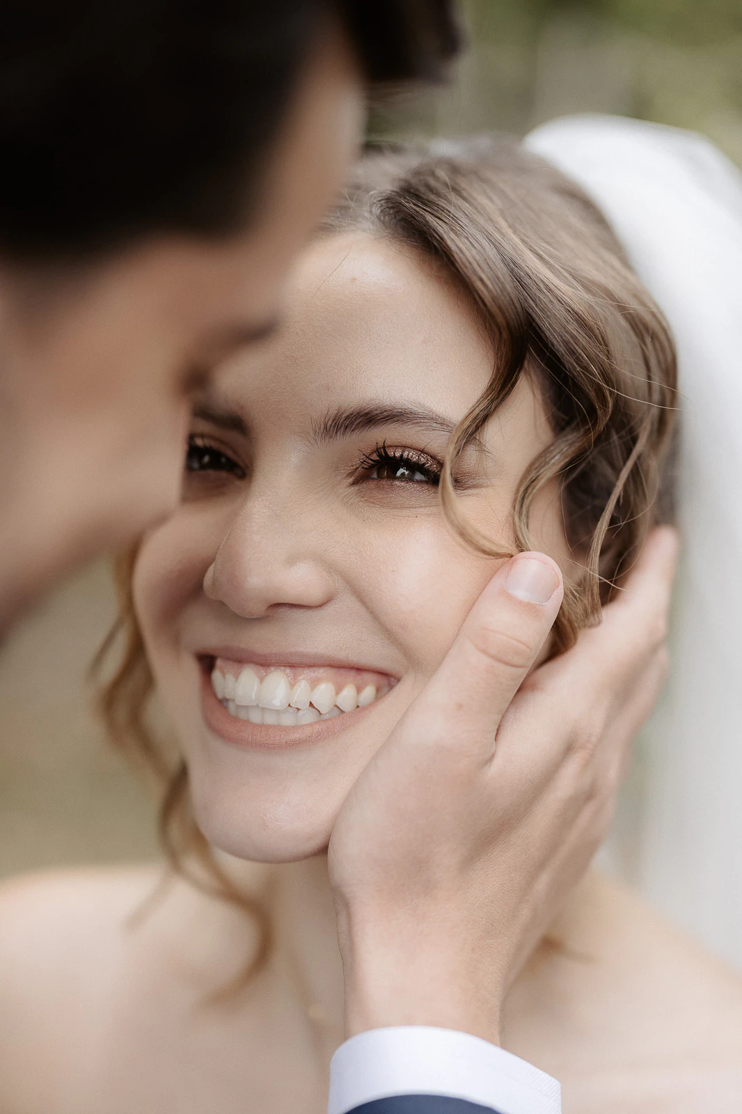 In sunlit Puglia, a groom tenderly cradles his bride’s face, her veil catching the light in an intimate wedding embrace.