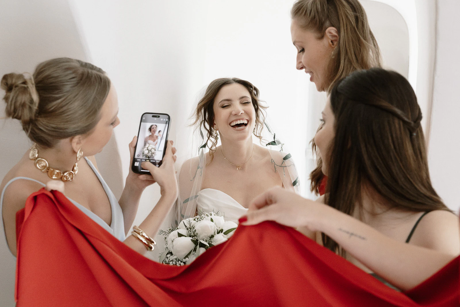 In sunlit Puglia, friends capture a radiant bride with bouquet, laughter and vibrant tradition infusing the elegant Italian celebration.