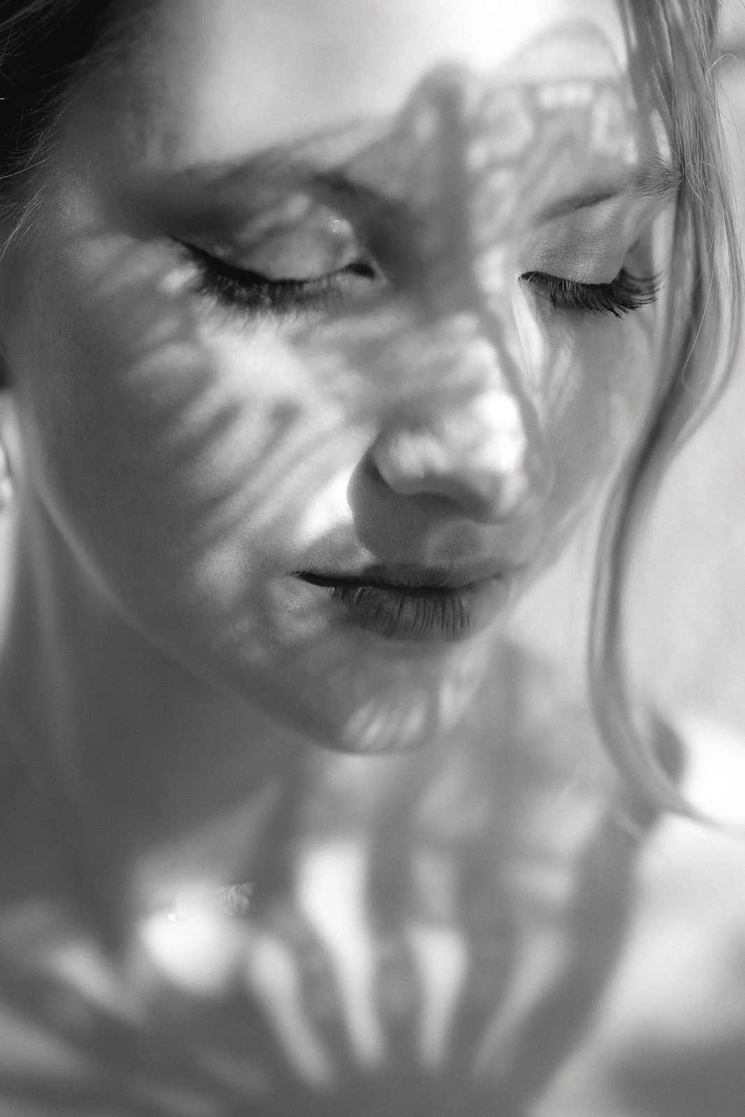 Elegant black and white portrait in Puglia, a bride’s closed eyes framed by delicate leaf shadows across her serene face.