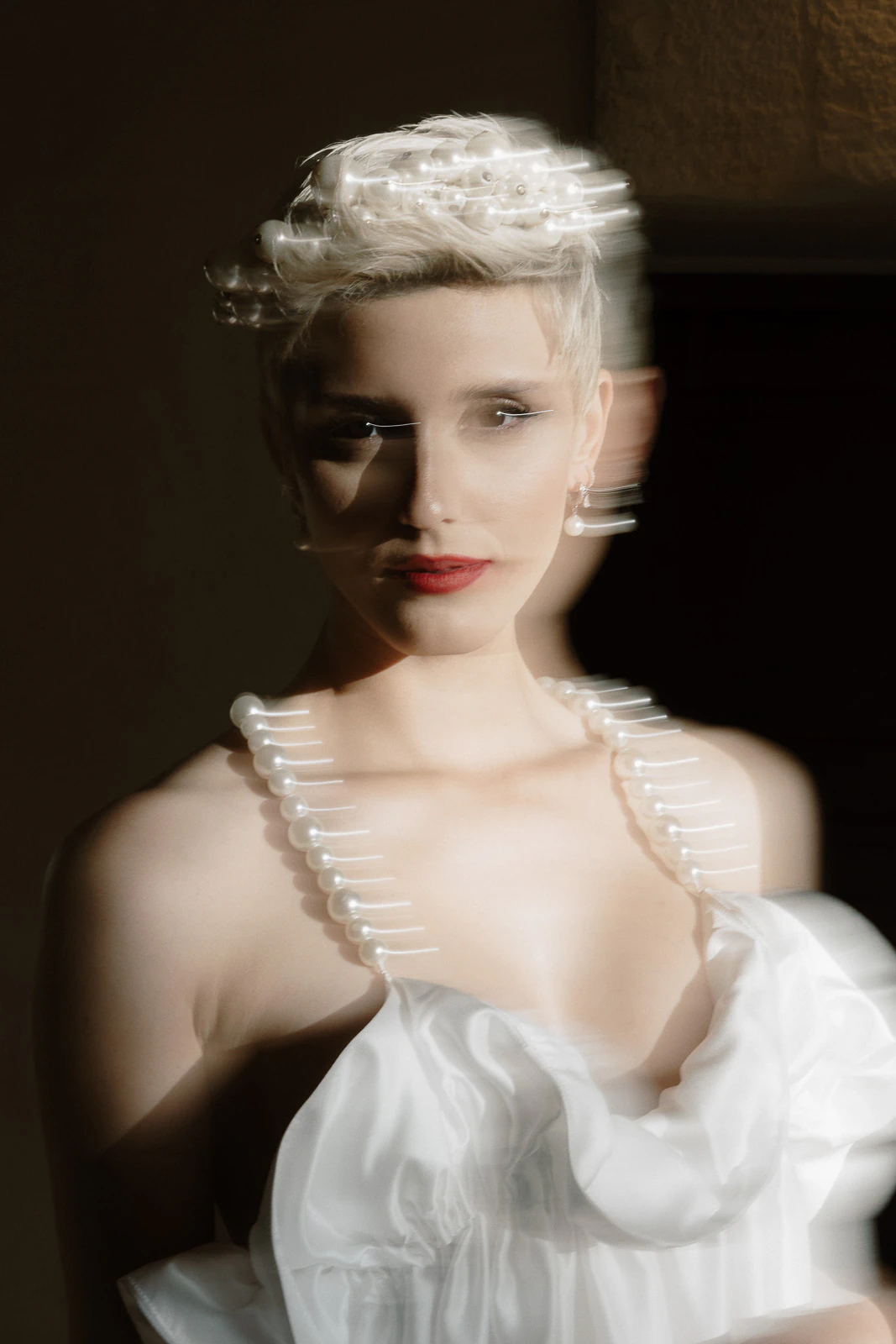 A bride in pearls and a white gown, framed by ethereal double exposure, evokes timeless romance in the heart of Puglia.