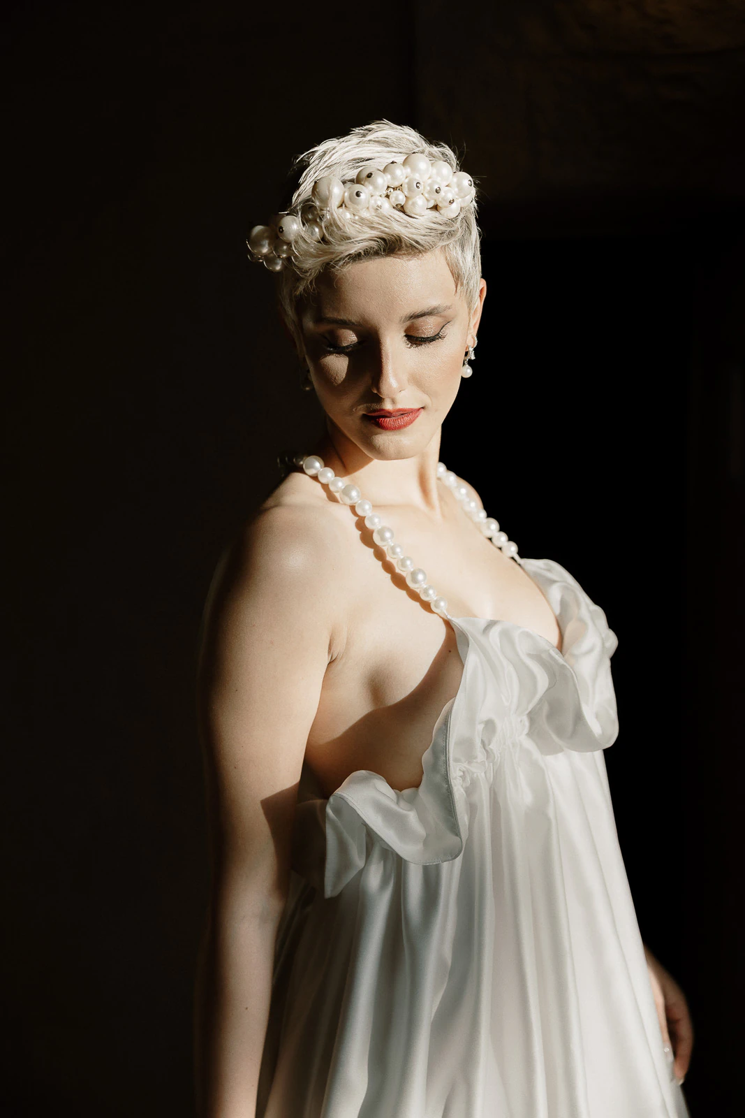 A bride in pearl-adorned ruffles glows in moody Italian light, evoking timeless romance at an elegant Puglia wedding.