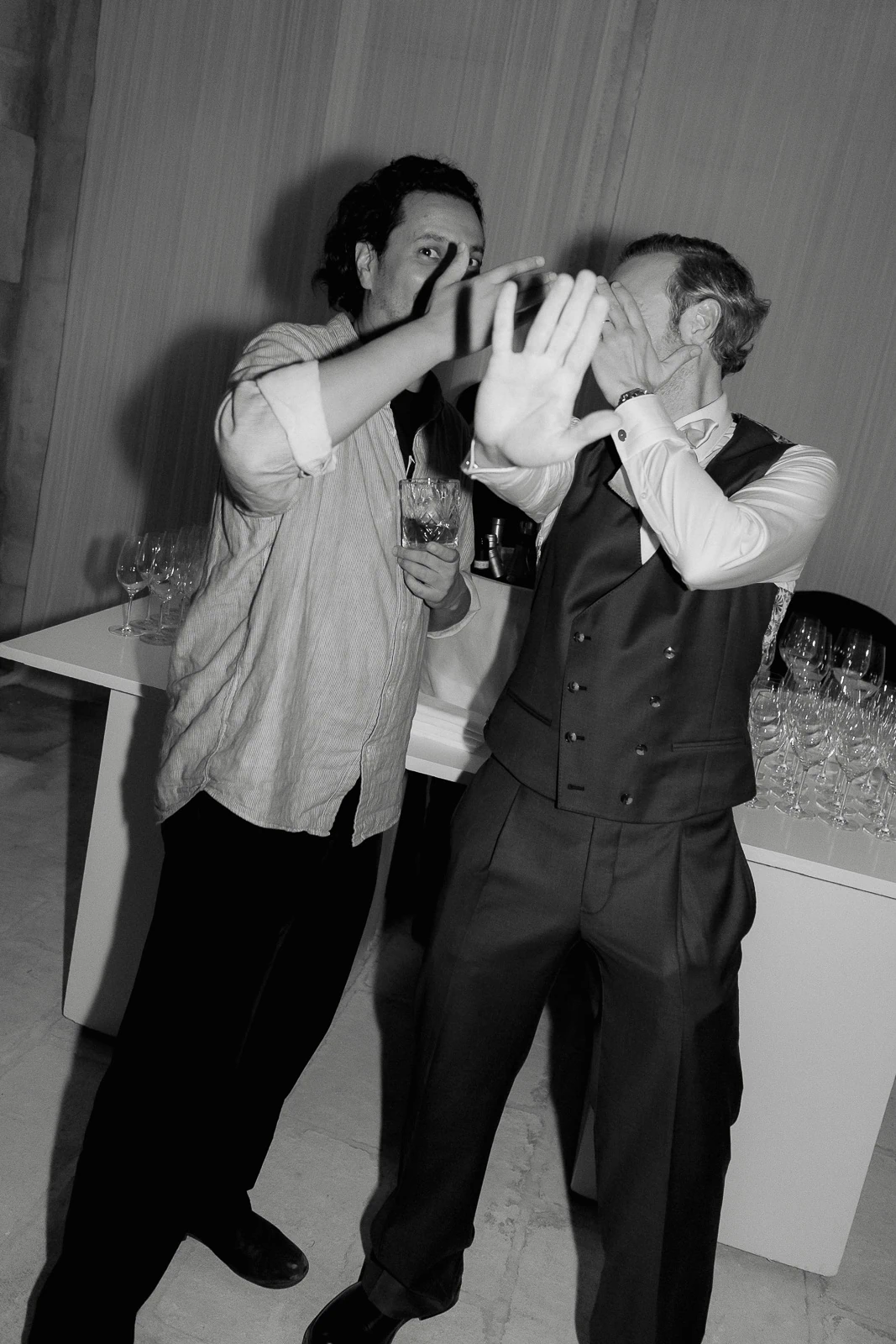 In timeless black and white, two men share a candid moment at an elegant Italian wedding reception in Puglia.