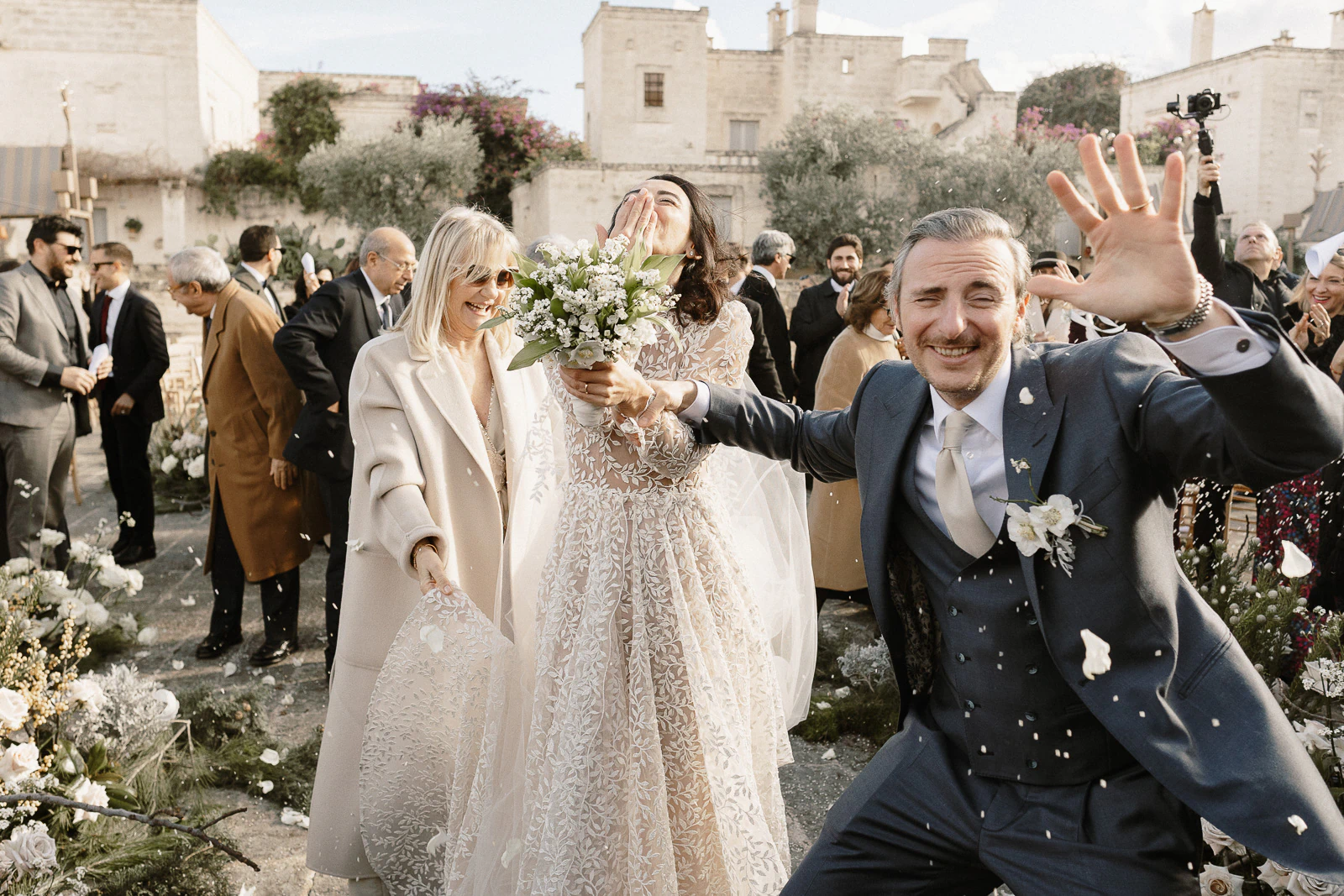 Amid Puglia’s sunlit gardens, a radiant bride shares laughter with guests as confetti floats through the Italian air.