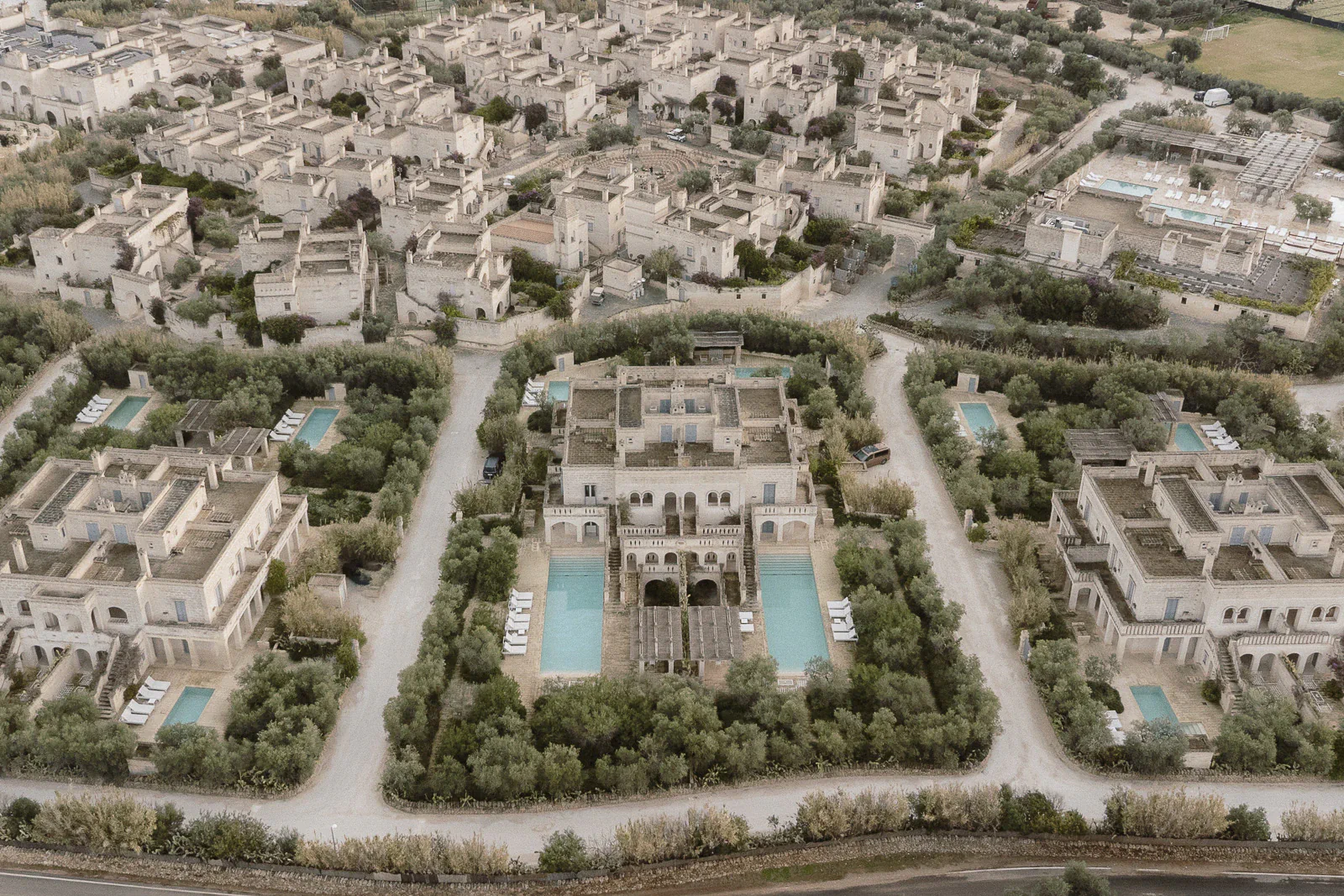 A romantic Puglian estate unfolds in perfect harmony, villas and pools nestled amid verdant gardens—an enchanting wedding retreat.