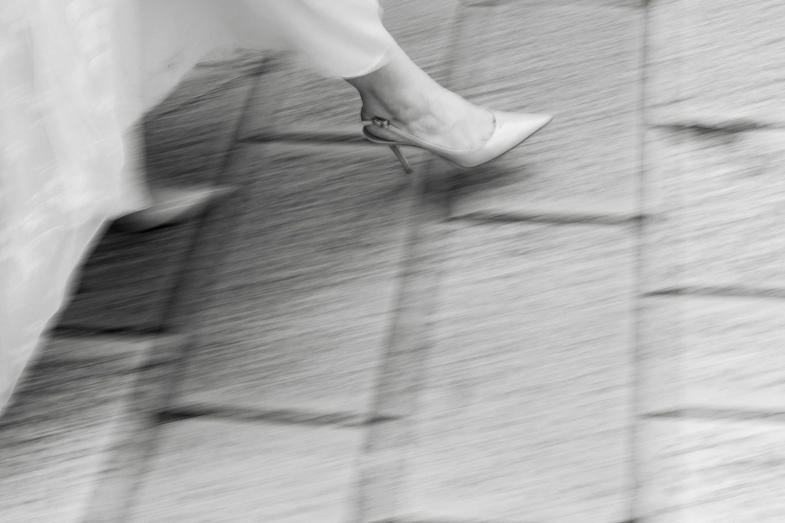 A moment in motion: gracefully walking in high heels, dress flowing, captured on stone pavements of Puglia in timeless black and white.