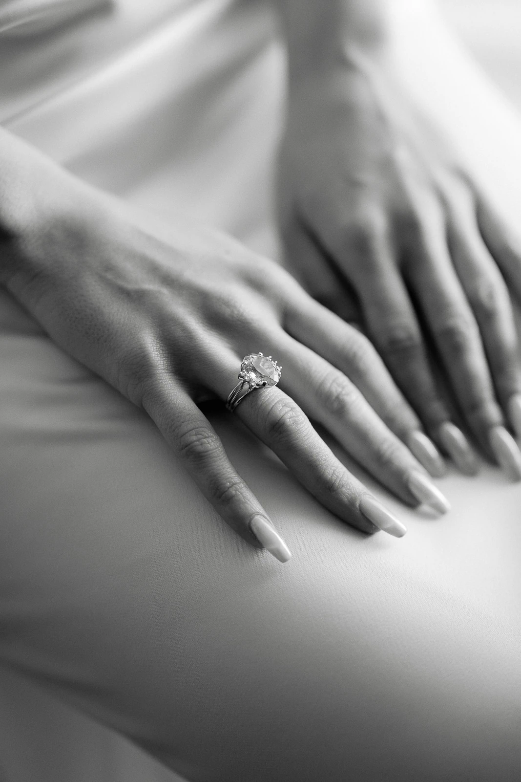Delicate hands intertwined on linen, a sparkling diamond ring and wedding band reflecting timeless romance in Puglia, Italy.