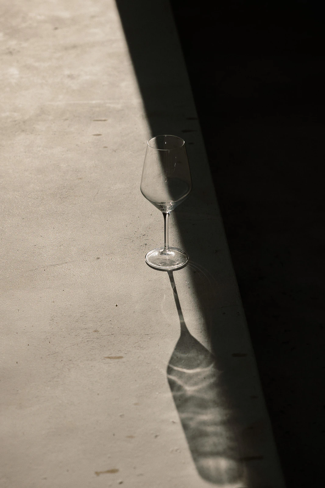 An empty wine glass rests on sunlit stone in Puglia, its delicate shadow echoing the romance of an Italian wedding evening.