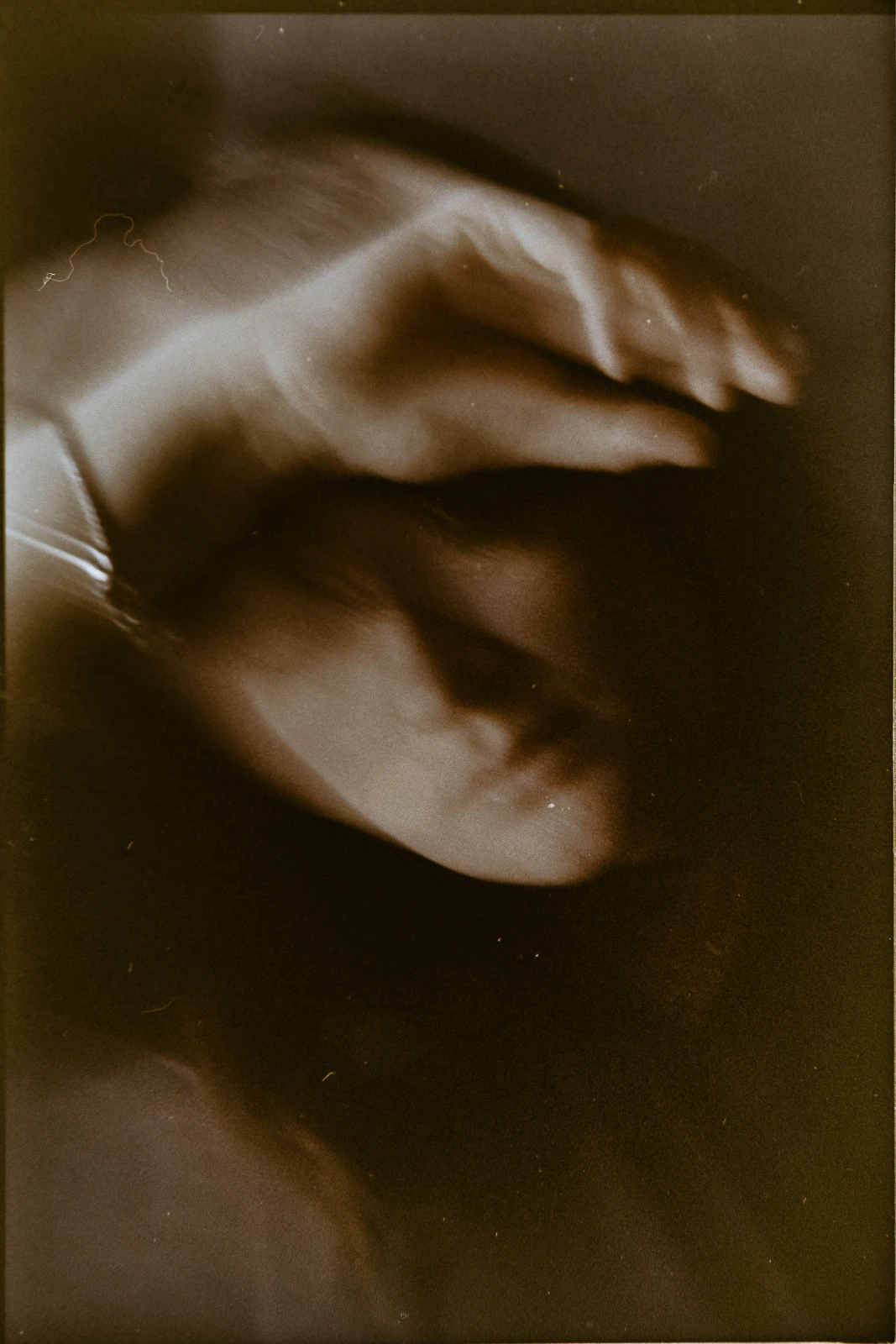 A softly blurred, sepia image captures an intimate moment in Puglia, a guest’s hand gently veiling their smile.
