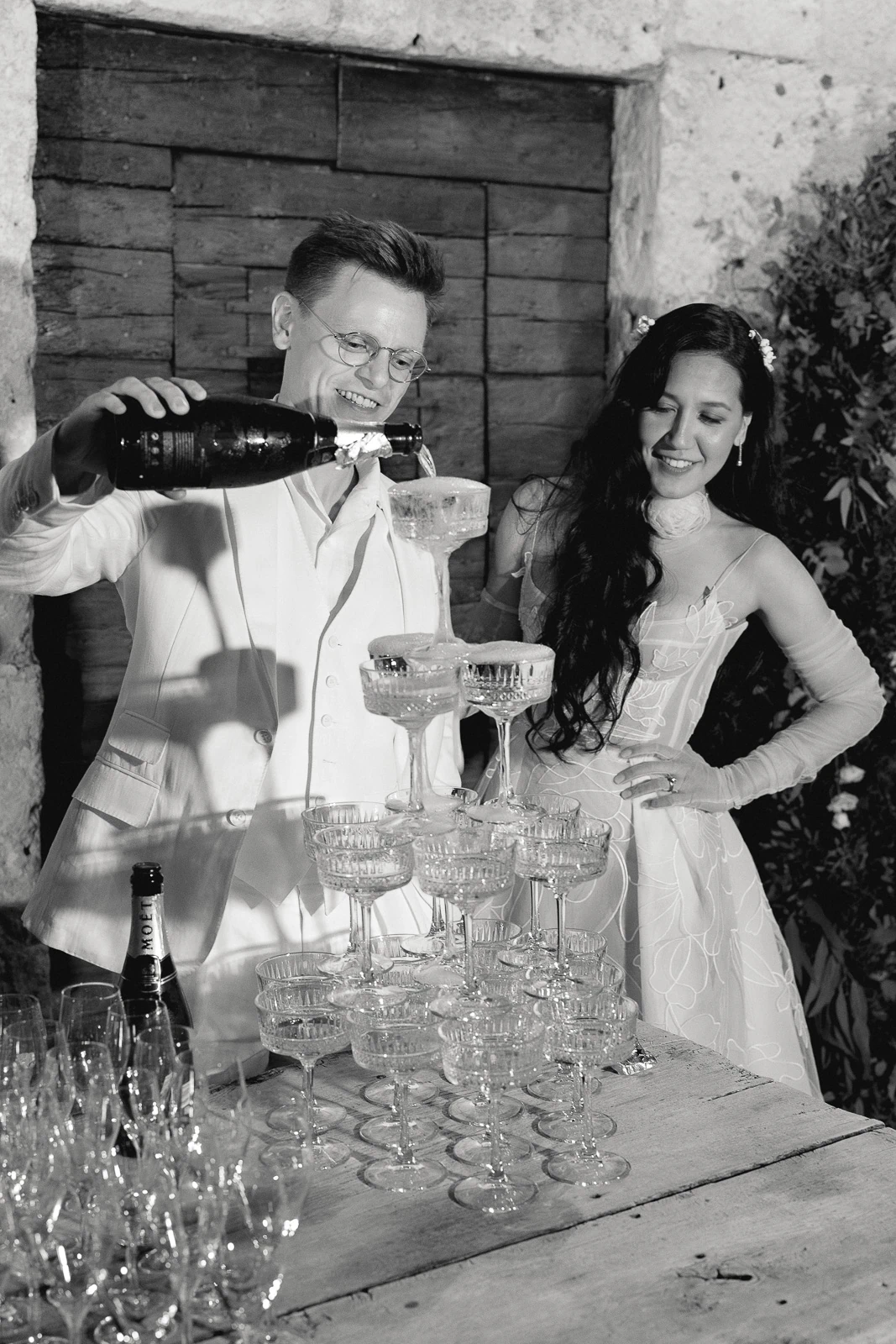 Amid Puglia’s romantic ambiance, a couple shares a joyful toast as champagne cascades into an elegant glass tower.