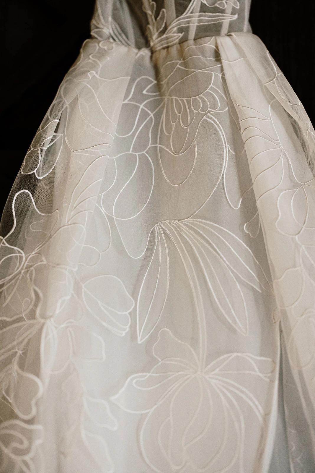 Delicate sheer white fabric, elegantly embroidered with oversized blooms, cascades in soft folds—perfect for a romantic Puglia wedding.