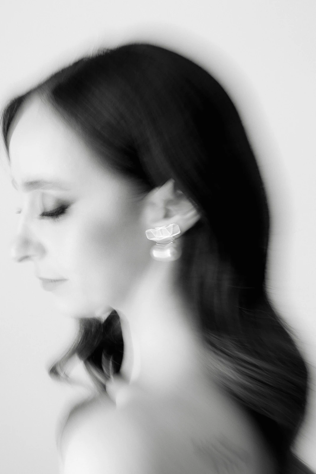 In Puglia, a woman’s long dark hair flows in motion, her geometric earrings highlighted in timeless black and white elegance.