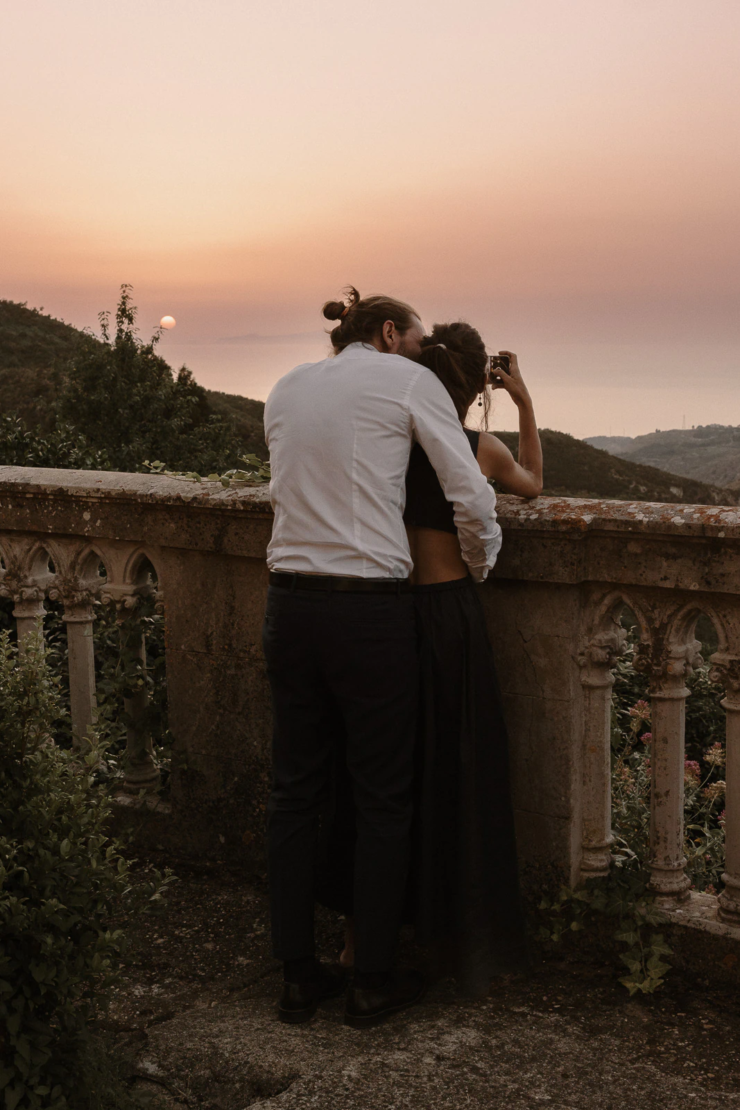 Embraced by the golden Puglian sunset, a couple savors quiet togetherness on a hillside terrace in southern Italy.
