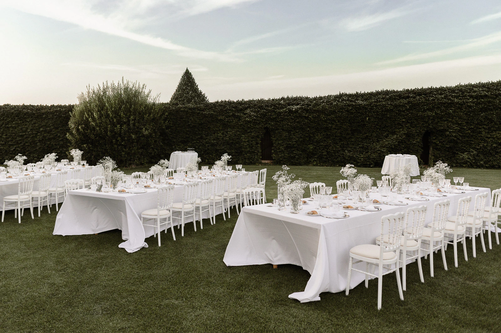 Elegant outdoor wedding reception in Puglia, Italy, with refined white tables set amid lush gardens and intimate alfresco ambiance.