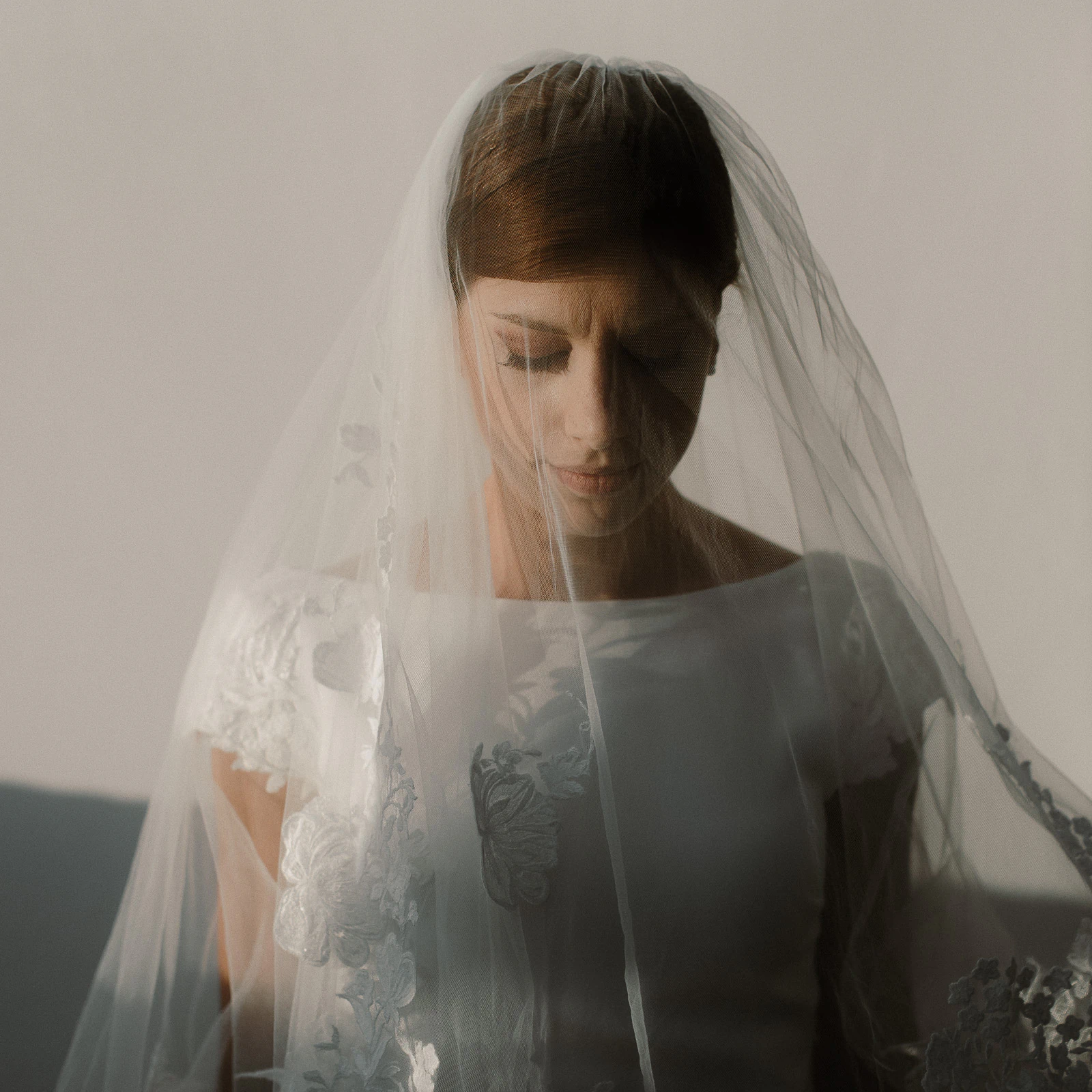 Soft Italian light bathes a bride in Puglia, eyes closed beneath a delicate veil, her silhouette graceful and serene.