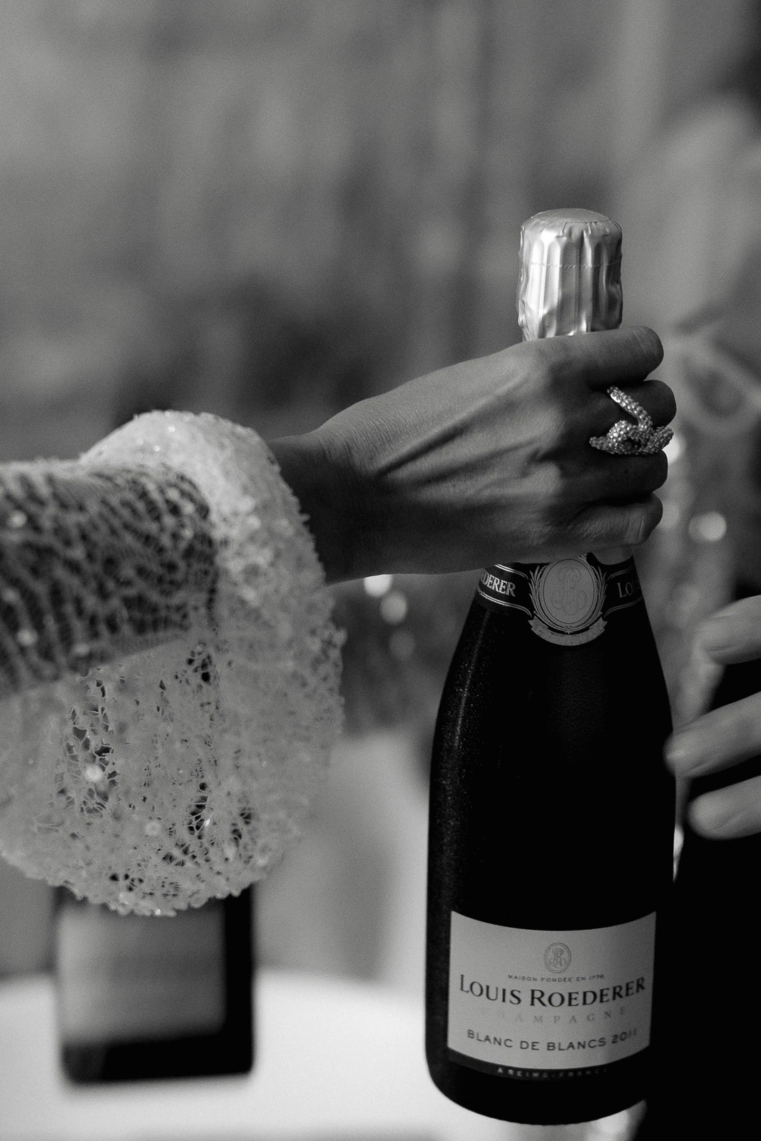 In a timeless black and white moment, two hands share Louis Roederer champagne—elegance unfolding at an Italian celebration.