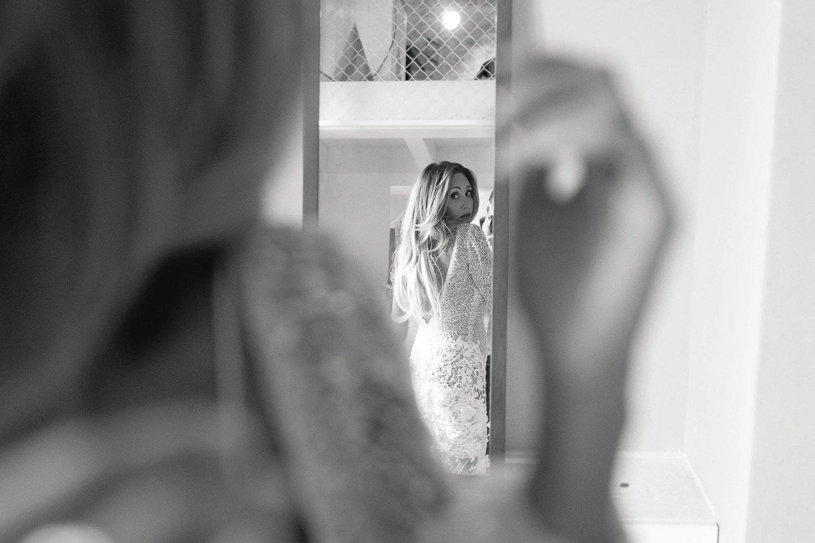 In an Italian villa, a bride in lace gazes thoughtfully at her reflection in a softly lit, black-and-white moment.