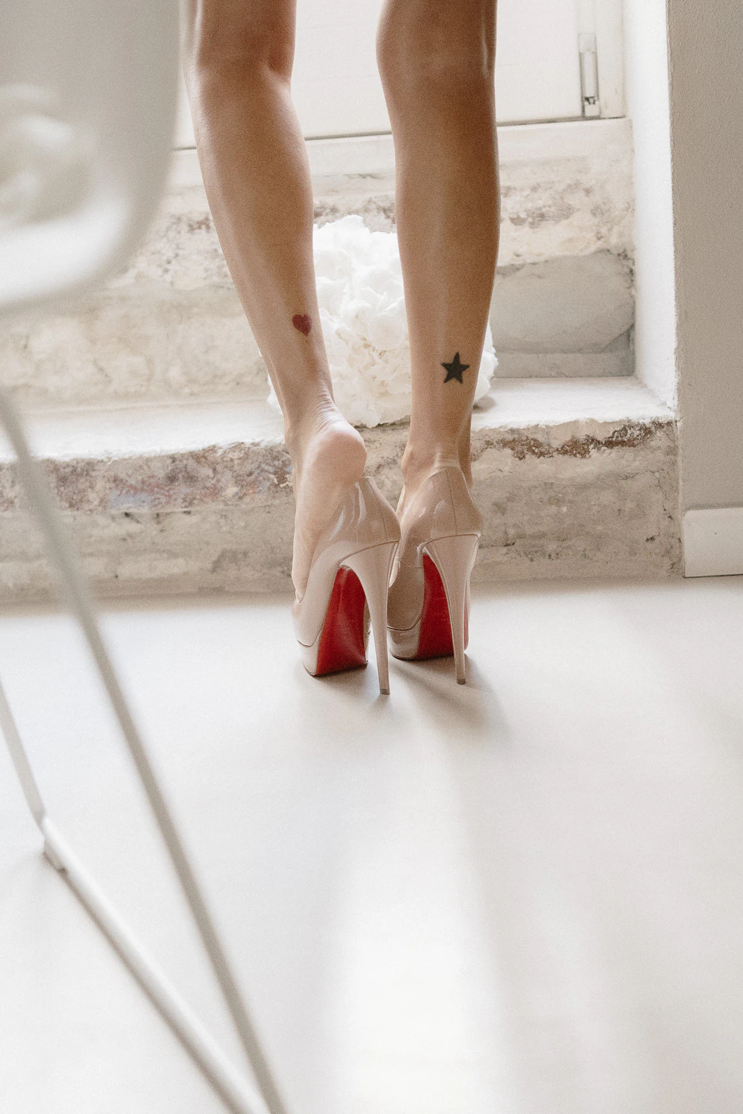 A bride stands on tiptoe in nude heels, heart and star tattoos visible—capturing romantic details of a Puglia wedding.