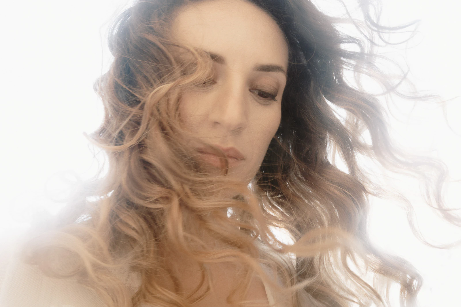 Bathed in soft Italian light, a bride’s wavy hair frames her pensive gaze—romance unfolding in timeless Puglian elegance.