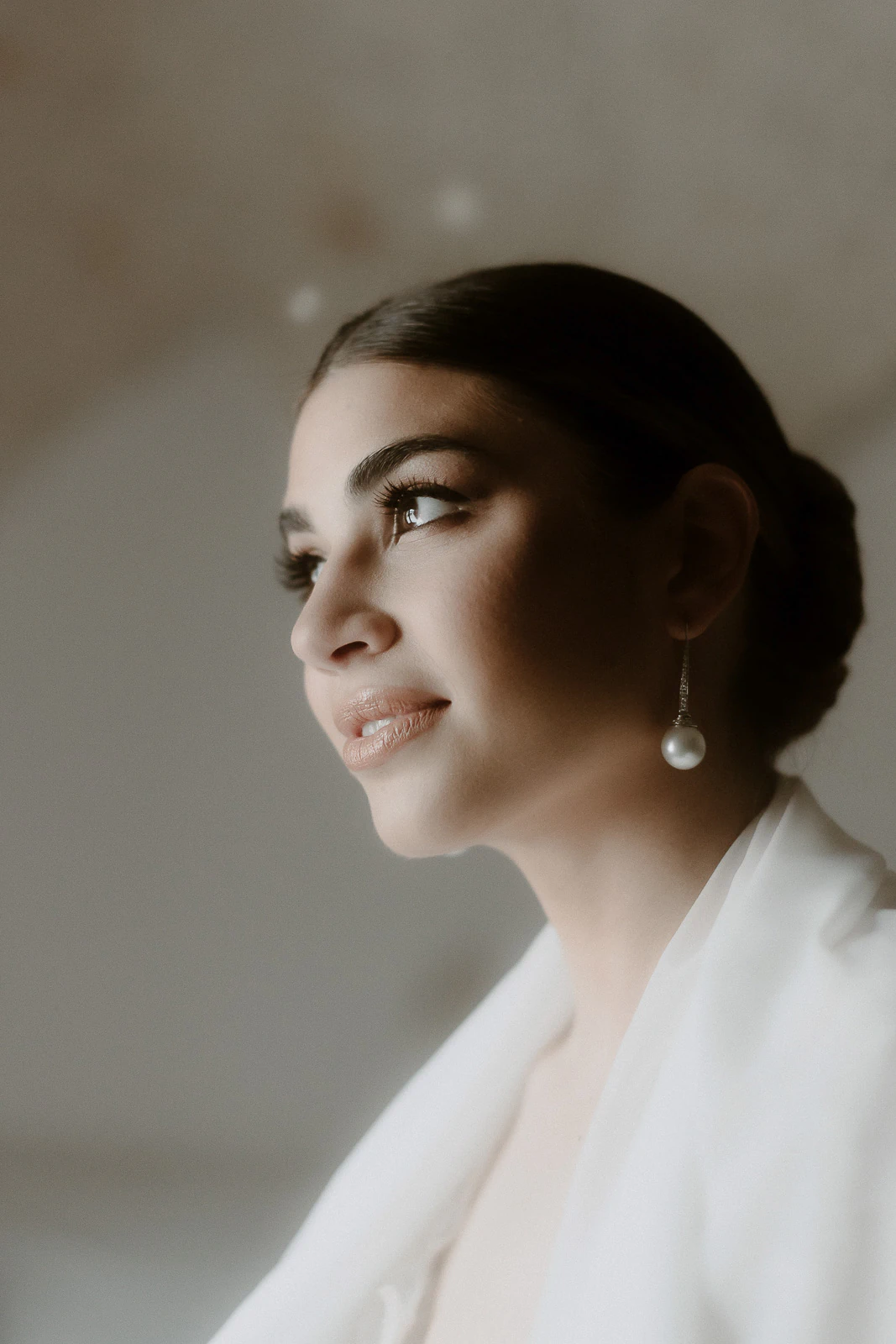 An elegant bride with pearl earrings gazes upward, bathed in soft Italian light—capturing timeless romance in Puglia.