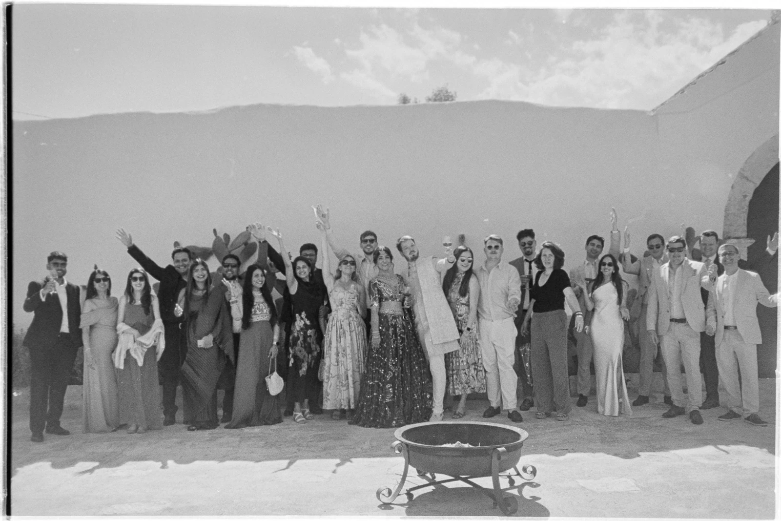 Elegant guests in formal attire gather beneath the Italian sun, sharing joyful moments at a stylish outdoor Puglia wedding.