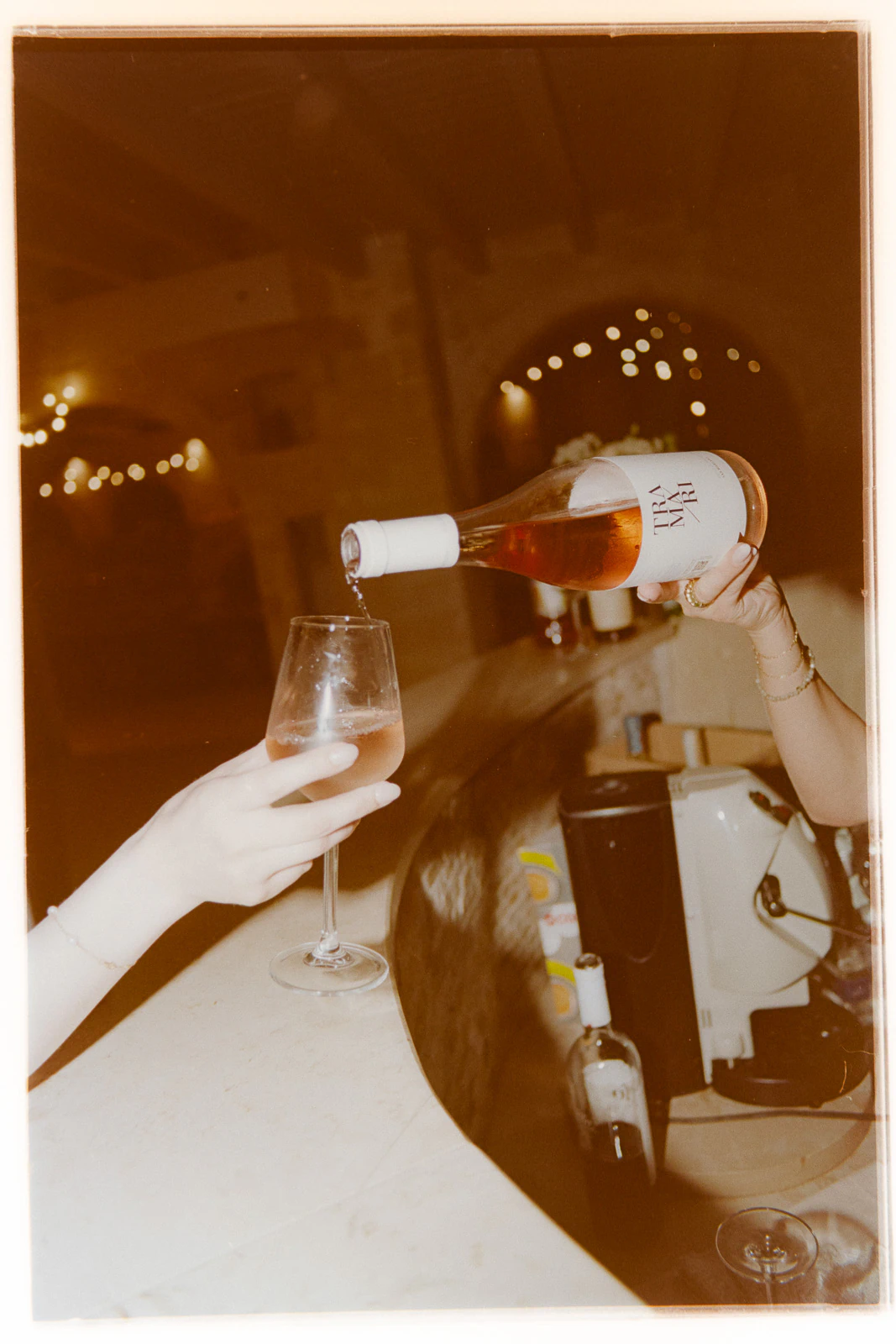 In Puglia, hands linger as rosé wine is gently poured, capturing intimate moments at an elegant Italian wedding bar.