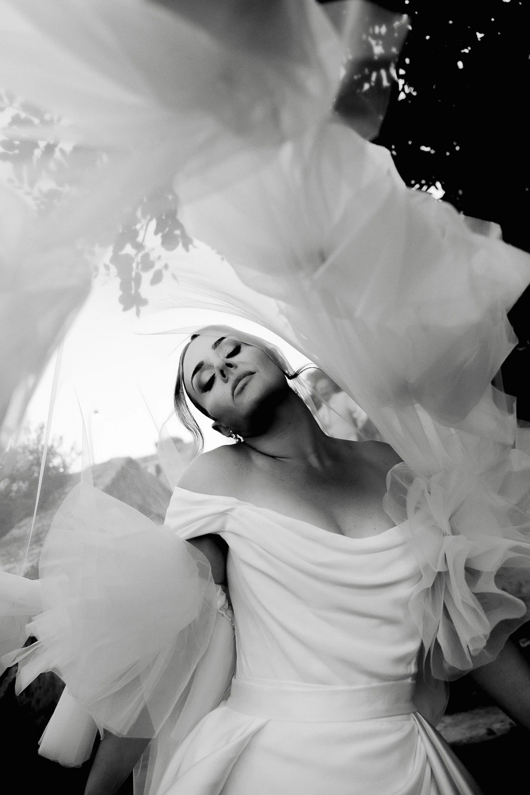 Bathed in Italian light, a bride in tulle closes her eyes, savoring the romance of a sunlit Puglia moment.
