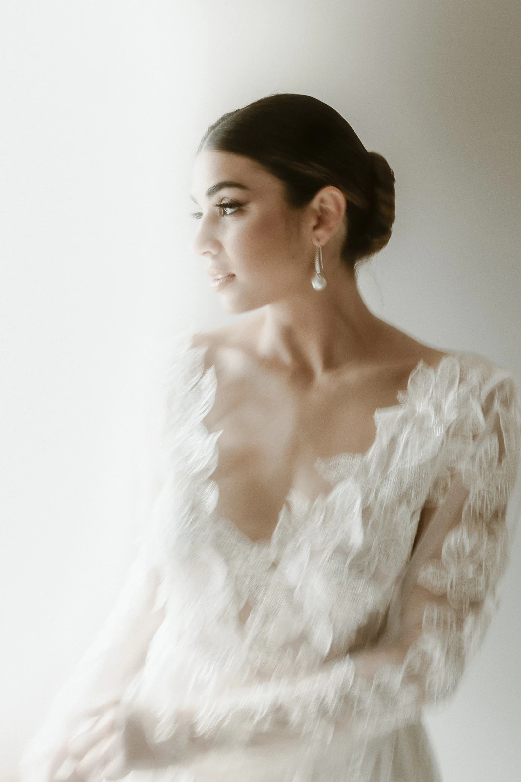Graceful bride in lace, low bun and pearl earrings illuminated by Puglia’s golden light, radiating timeless Italian elegance.