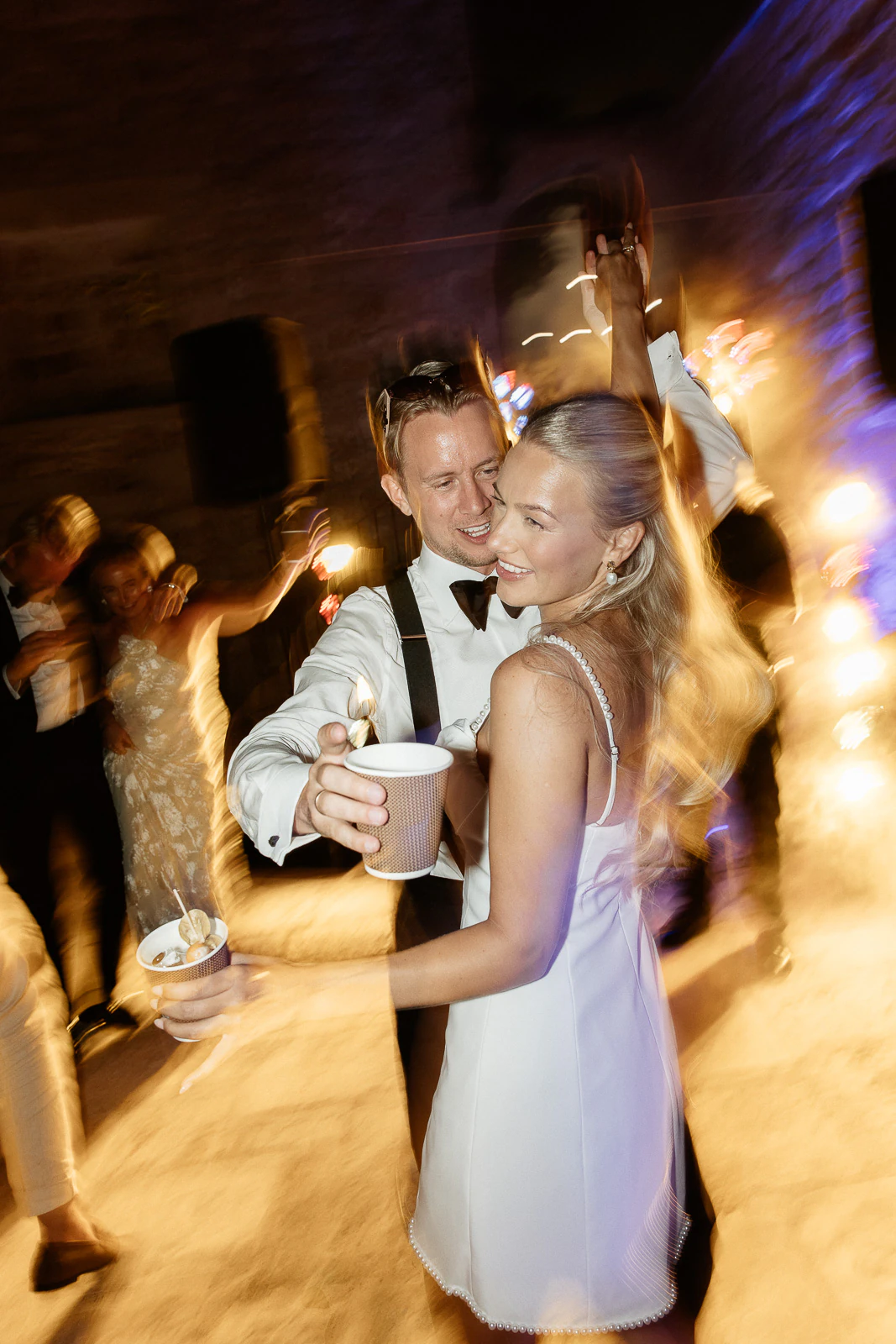 Elegant couple sharing a joyful dance at a candlelit Puglia wedding, their laughter blending into the vibrant Italian celebration.