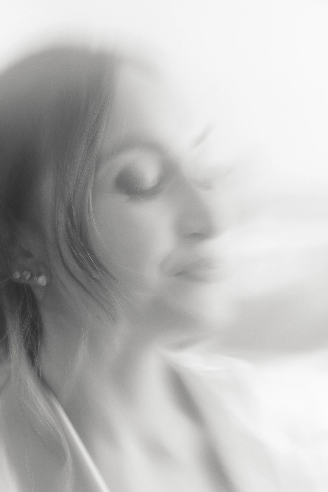 In Puglia, a bride softly smiles with closed eyes, ethereal in black and white, exuding serene elegance and intimate emotion.