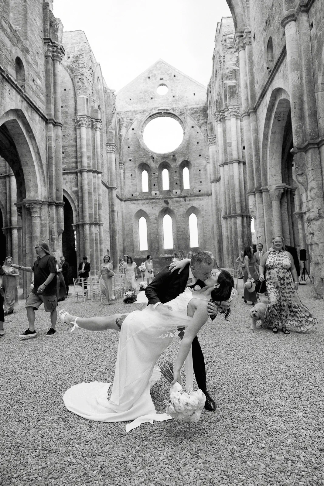 Amidst ancient stone ruins in Puglia, newlyweds share a romantic dip and kiss as guests look on in celebration.