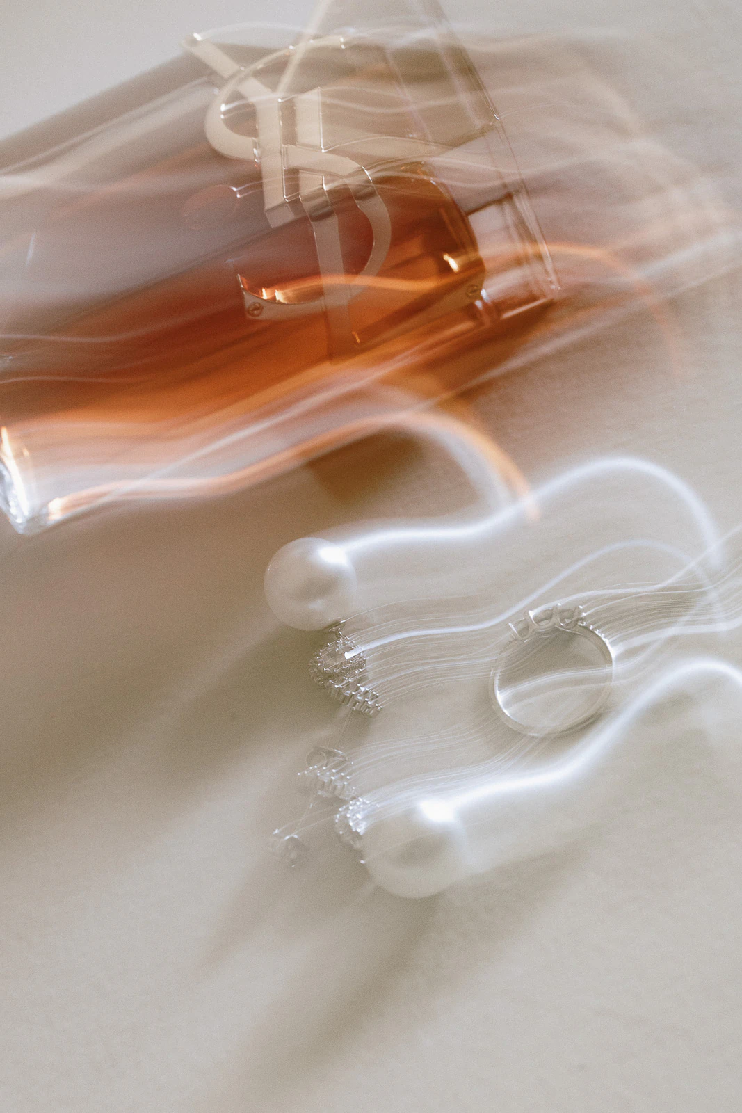 A silver ring and pearl earrings rest beside a spilled rosé glass, capturing romantic motion at a Puglia destination wedding.
