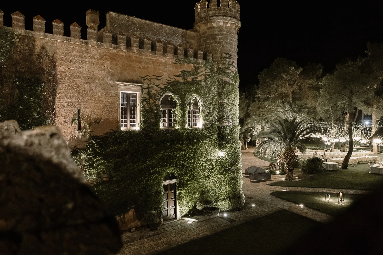Under twinkling lights, an ivy-clad stone villa in Puglia exudes Italian romance, perfect for intimate outdoor celebrations.